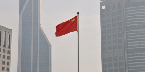 The Chinese flag in front of skyscrapers.